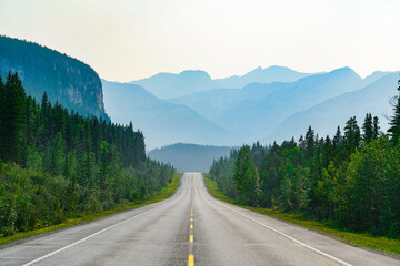 A summer view down a mountain highway in Alberta with smoke clouding the view.