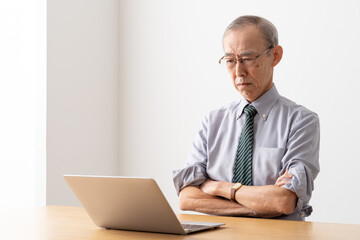 パソコンを見てしかめっ面をするシニアビジネスマン