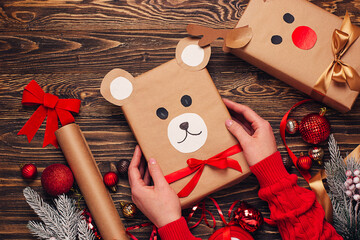 Girl hold creatively wrapped Christmas gift in the shape of a teddy bear and a deer. New Year and Christmas concept. DIY gift wrapping