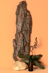 Serum or essential oil in glass bottle with pipette on beige background with tree bark, branch, stone. Concept of natural organic cosmetics. Mockup, front view.