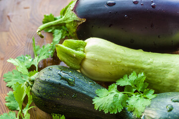 Still life - fresh whole zucchini, eggplant and parsley on a wooden board, close up