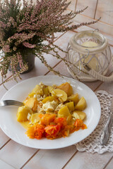 boiled potatoes with peper salad on the white plate, shabby wooden background