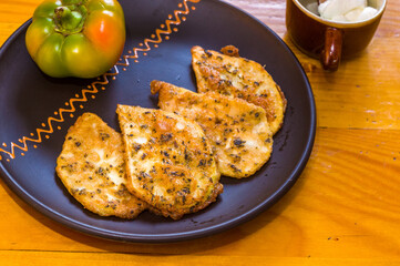 Vegetarian food - celery tuber slices fried in batter in a ceramic plate on a wooden table, close up