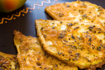 Vegetarian food - celery tuber slices fried in batter in a ceramic plate on a wooden table, close up