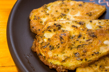 Vegetarian food - celery tuber slices fried in batter in a ceramic plate on a wooden table, close up