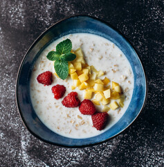 oatmeal with raspberries, mango, mint in a blue plate