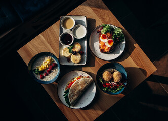 breakfast plates on the table. curd pancakes, toast with salmon, oatmeal with fruit, lavash with vegetables