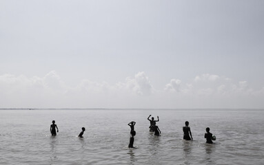 Naklejka premium Local young boys taking a bath ,swimming and playing ball in the Padma river in a hot summer day noon