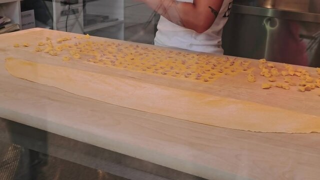 Italian Tortellini pasta hand made. Making home-made ravioli or tortellini with spinach and ricotta or ham speck and cheese filling.