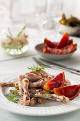 Grilled Frog Legs Garnished with Blood Orange Slices and Fresh Lettuce