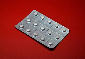 Blister pack of white pills on red background