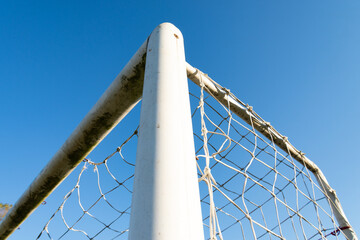 The top corner of a soccer goal post from below on a blue sky background