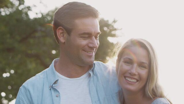 Portrait of loving couple in countryside hugging and kissing against flaring sun - shot in slow motion