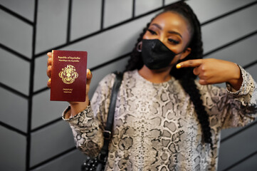 African woman wearing black face mask show Seychelles passport in hand. Coronavirus in Africa country, border closure and quarantine, virus outbreak concept.