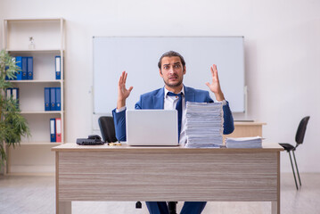 Young male employee and too much work in the office