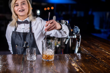 Charming woman barman places the finishing touches on a drink at the night club © Mr. Prof