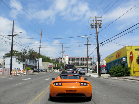 Orange Tesla Sports Car on road in Kaimuki