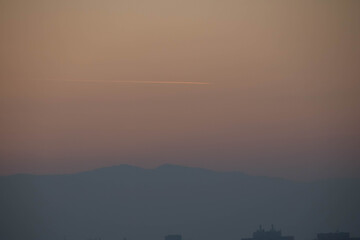 View of a hill during sunset with trace of plane