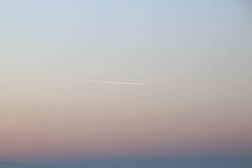 Trace of airplane in the middle of the sky during sunset and the sky is gradient.