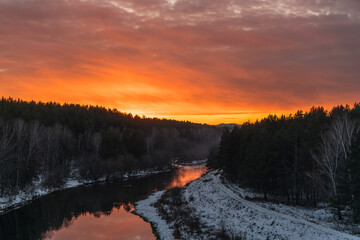 Winter river and forest on the background of the sunset. Beautiful landscape nature background