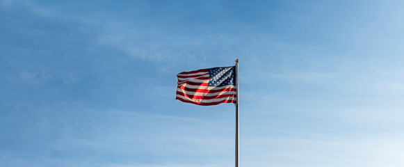 Flagpole with American flag waving on the wind on blue sky background. Country symbol banner, USA president elections, Independence and Memorial Day.