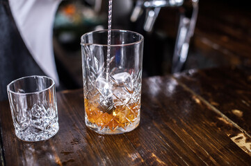 Charming woman mixologist demonstrates his skills over the counter behind the bar