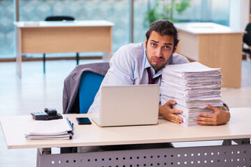 Young male employee unhappy with excessive work in the office