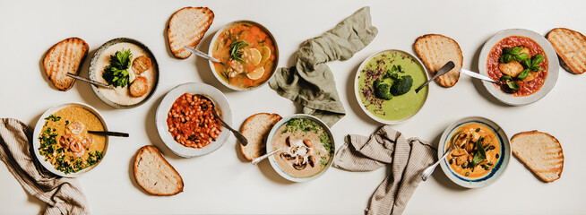 Flat-lay of vegetarian creamy homemade soup with bread slices over white plain table background,...