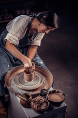 Close-up A woman potter in beautifully sculpts a deep bowl of brown clay and cuts off excess clay on a potter's wheel in a beautiful workshop