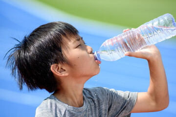 Young boy drink water from a bottle.