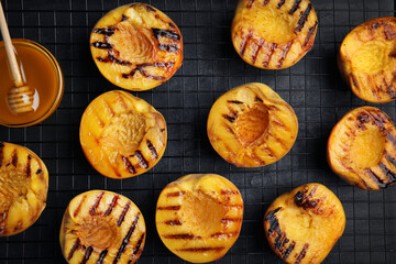 Delicious grilled peaches and honey on black table, top view