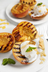 Delicious grilled peaches with ice cream served on white table, closeup