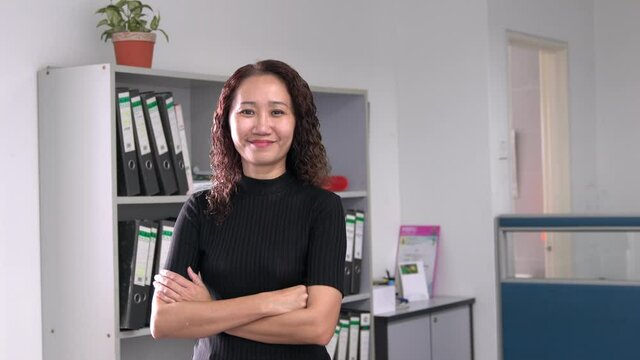 Portrait of an Asian businesswoman smiling, confident. Office setting.