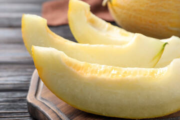 Pieces of delicious honeydew melon on wooden board, closeup