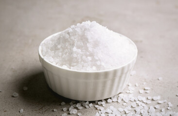 Bowl with salt on light grey table, closeup