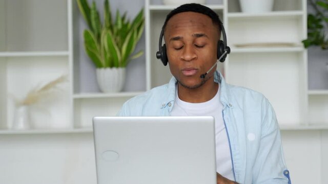 Focused black consultant with a headset looks at a laptop
