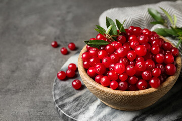 Tasty ripe cranberries on grey table, closeup. Space for text