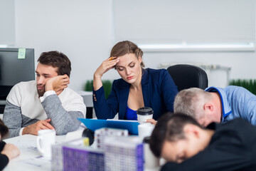 Business people sleeping in the conference room during a meeting, while their colleague is trying to concentrate on the documents she is studying.