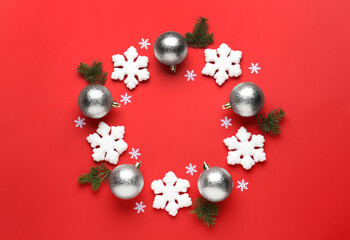Beautiful festive wreath made of silver Christmas balls and snowflakes on red background, top view