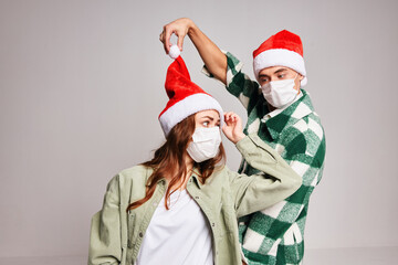 man and woman wearing santa hats christmas fun medical masks studio