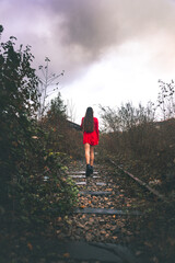 Young elegant woman with a red dress walking at old a rail way.