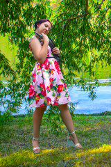 A smiling woman in a pink dress holding a large brown flathead catfish.