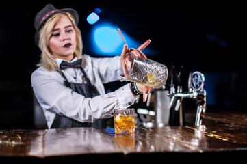 Charismatic girl barman mixes a cocktail in the pub