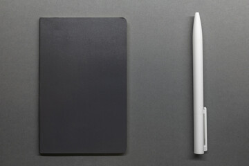 grey notebook and white pen on table flat lay