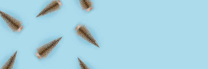 Christmas pattern of golden christmas trees on light blue background. Flat lay, top view, copy space.