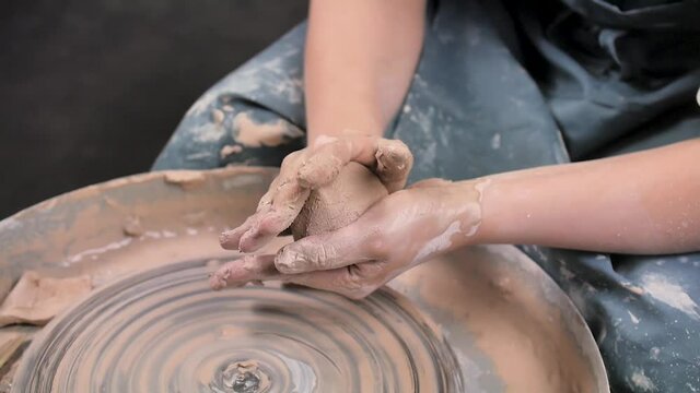 Pottery girl works with clay on a potter's wheel. Handicraft production. Close-up.
