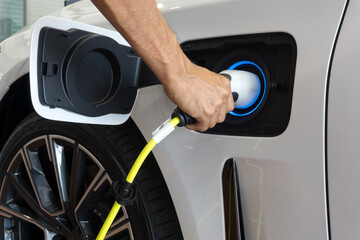 Man hand is holding Electric car charging connect to elecric car on charge station, Electric mobility environment friendly 	