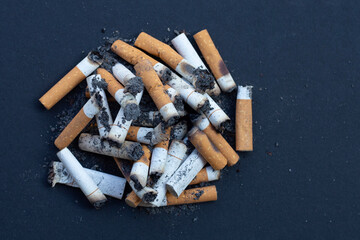 Cigarette butts on dark background.