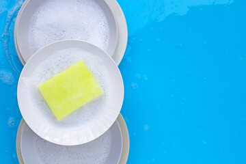 Washing dishes concept on wet blue background. Top view