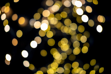 Blurred abstract gold glitter texture, defocused christmas lights on black background. Holiday christmas concept.